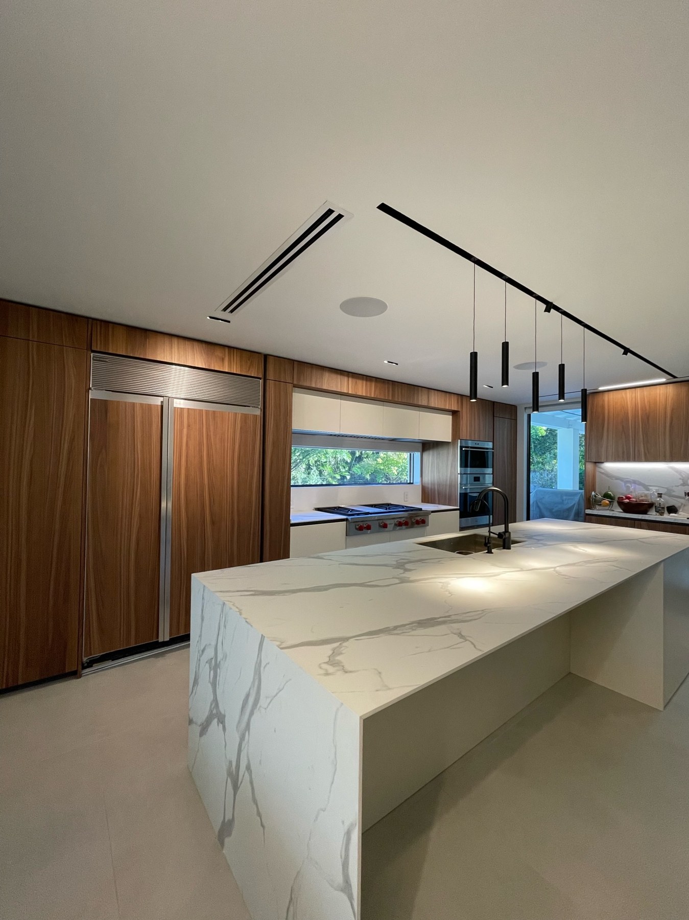 Completed CJL kitchen renovation with warm wood cabinetry and a stone waterfall island